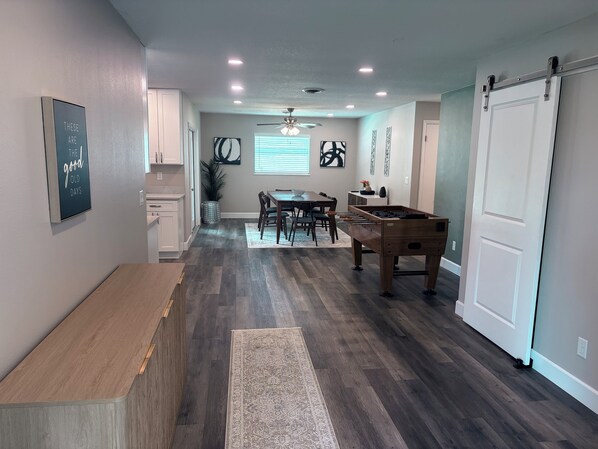 A modern kitchen with a dining area, wooden flooring, and a foosball table.