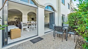 Un pati exterior modern amb zona de menjador, una banca de vimet i una taula petita.