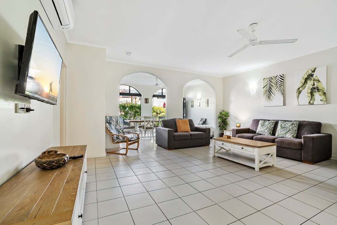 A spacious living area with a flat-screen TV, two sofas, a coffee table, and a dining table with chairs.