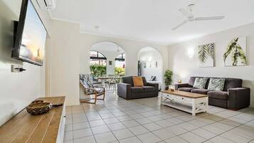 A spacious living area with a flat-screen TV, two sofas, a coffee table, and a dining table with chairs.