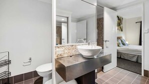 Un bany modern amb un mirall gran, un lavabo blanc i un vàter.