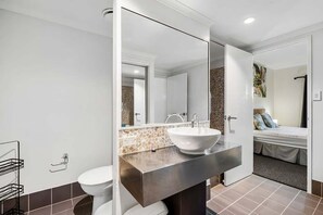A modern bathroom with a large mirror, a white sink, and a toilet. - Mango Resort 2 Bedroom Pool Access 11 (Palm Cove)