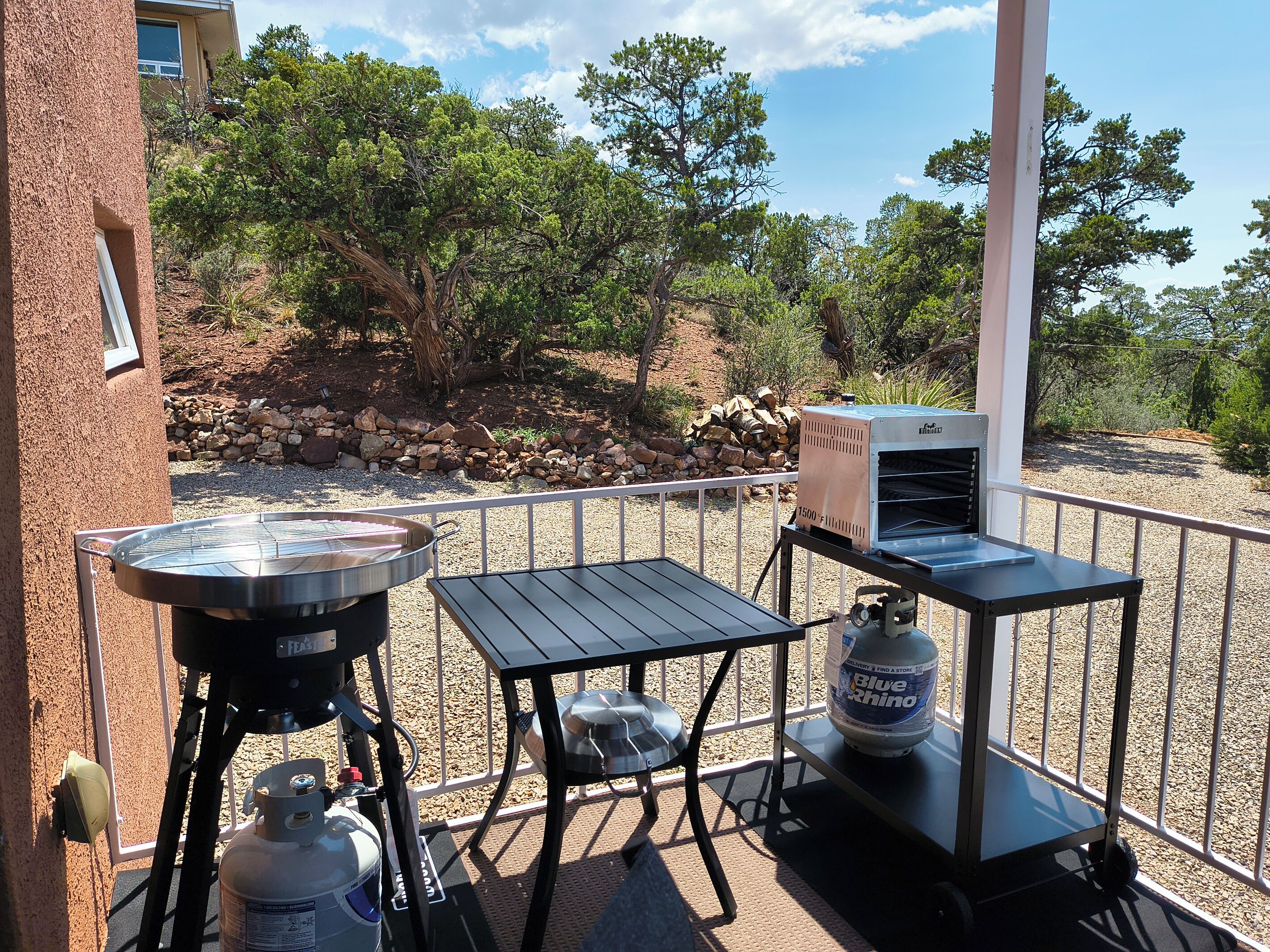 An outdoor barbecue area with a grill, tables, and a propane tank.