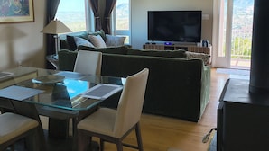 Ein Wohnzimmer mit einer Couch, einem Flachbildfernseher, einem Esstisch mit Stühlen und einem Deckenventilator.