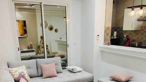 A modern living room with a grey sectional sofa, a white coffee table, and a small white table.