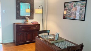 A dining area with a wooden table, chairs, a mirror, and a framed picture on the wall.