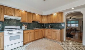A kitchen with wooden cabinets, a white stove, and a patterned floor.