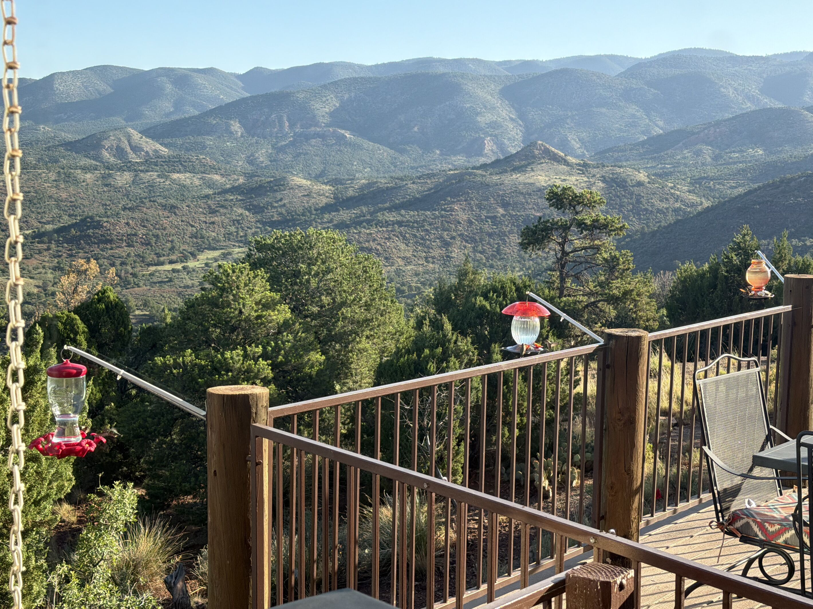 A wooden deck with a railing overlooking a mountainous landscape.