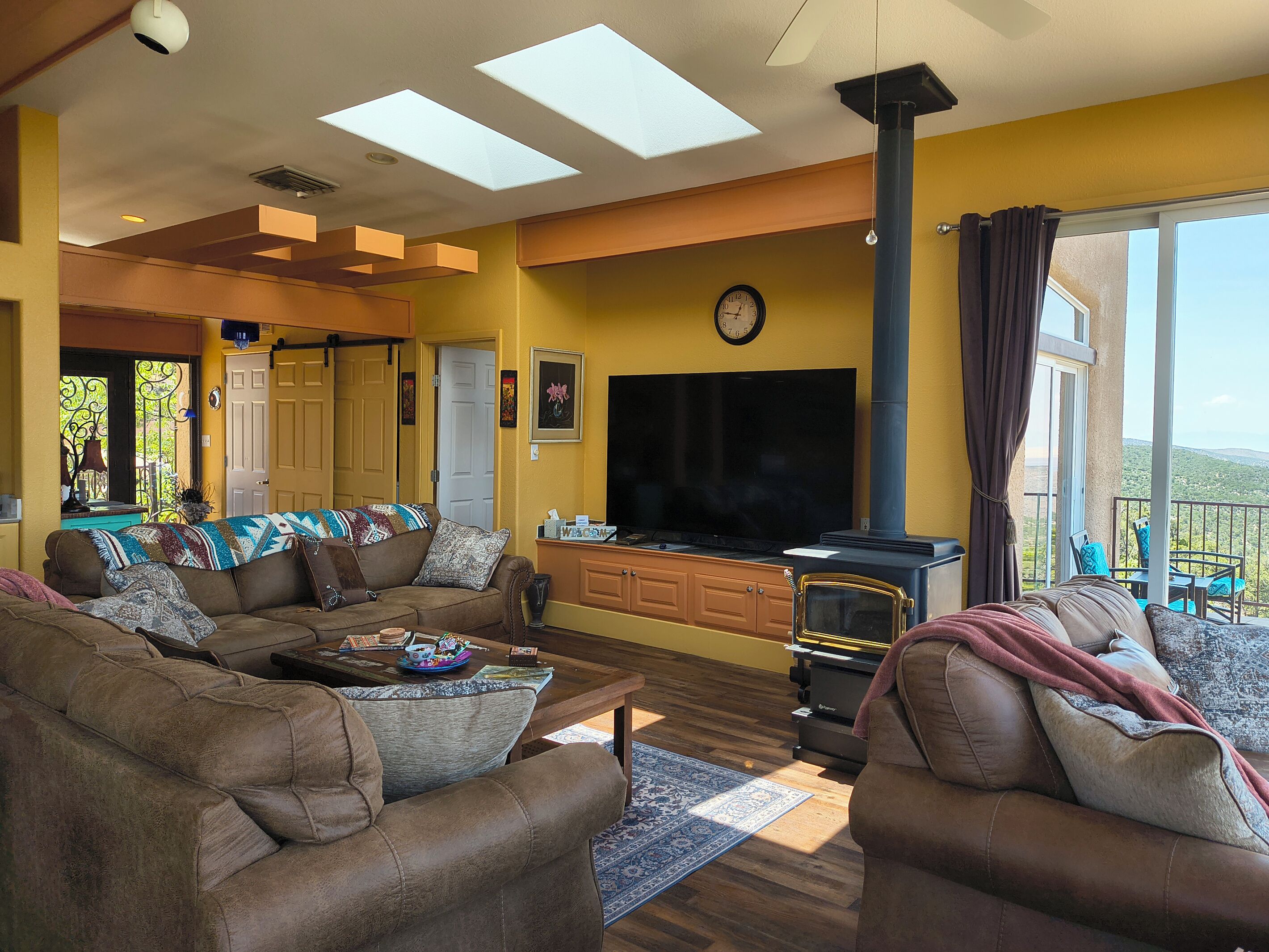 Una sala de estar con sofá, televisor de pantalla plana, chimenea y balcón con mobiliario exterior.