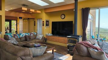 Una sala de estar con sofá, televisor de pantalla plana, chimenea y balcón con mobiliario exterior.