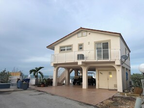 Ein zweistöckiges Gebäude mit Balkon, Garage und Meerblick.