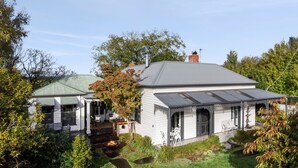 Una casa bianca con tetto grigio, circondata da alberi e un giardino.