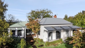 A white house with a grey roof, surrounded by trees and a garden. - Grenville House - Beautiful Victorian home with garden in the heart of Daylesford (Daylesford)