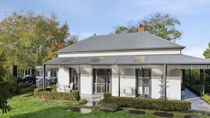 Una casa a due piani con un portico coperto, un camino e un giardino.