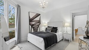 Una camera da letto con un letto grande, comodini, un lampadario e vista sull'esterno.