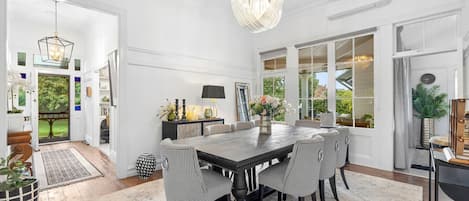 A spacious dining area with a large table, black and white checkered chairs, and a chandelier.