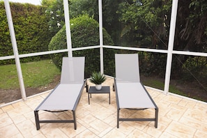 Une véranda avec deux fauteuils, une petite table et une plante en pot.