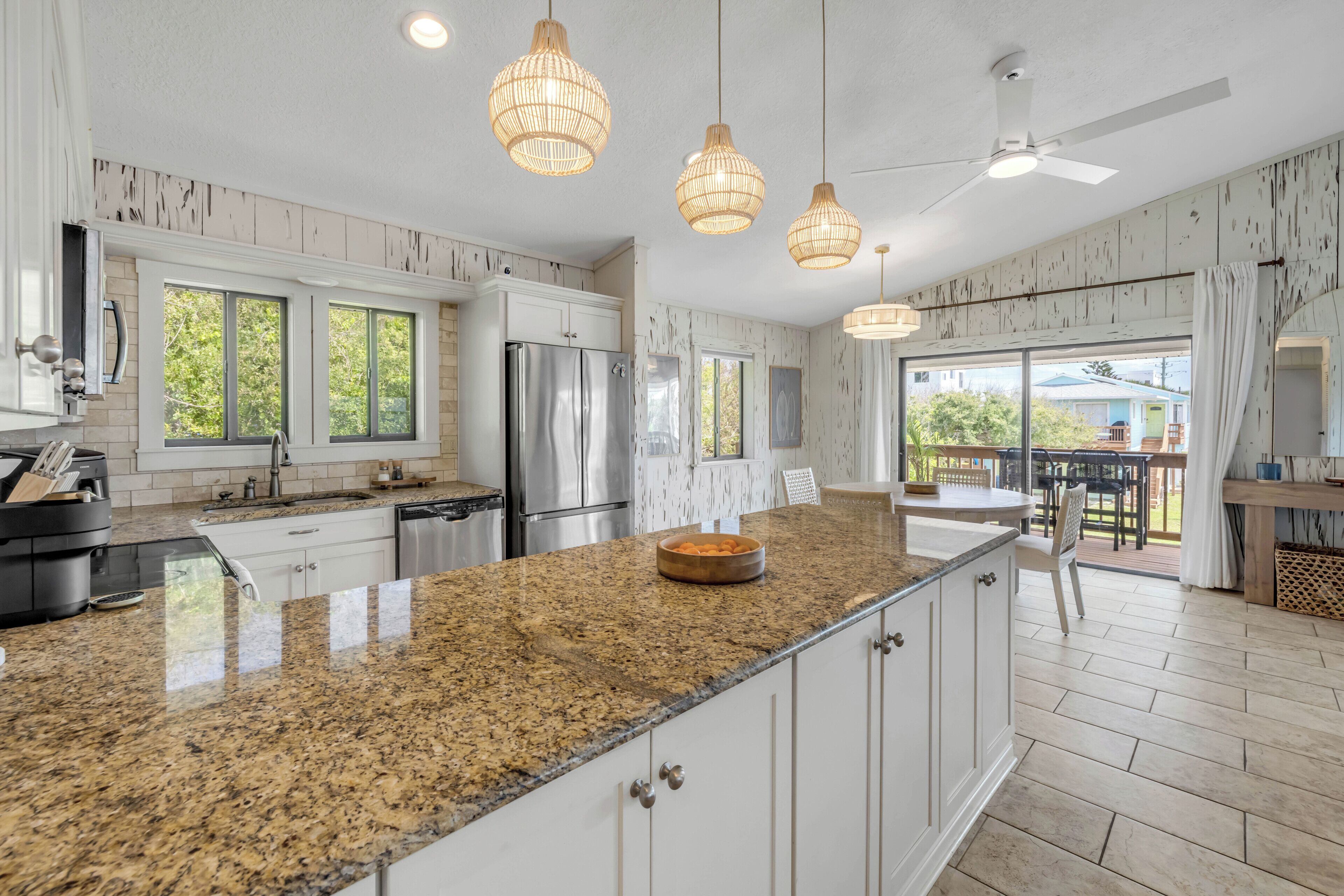 A modern kitchen with granite countertops, stainless steel appliances, and pendant lighting.