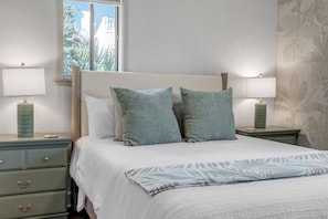 A bedroom with a bed, two nightstands, a window, and a wall with a leaf pattern. - Bethune Beach 4BR Home with Rooftop Deck Walk to Beach and Indian River (New Smyrna Beach)