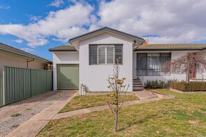 Ein eingeschossiges Haus mit Garage, kleinem Vorgarten und einem Baum.