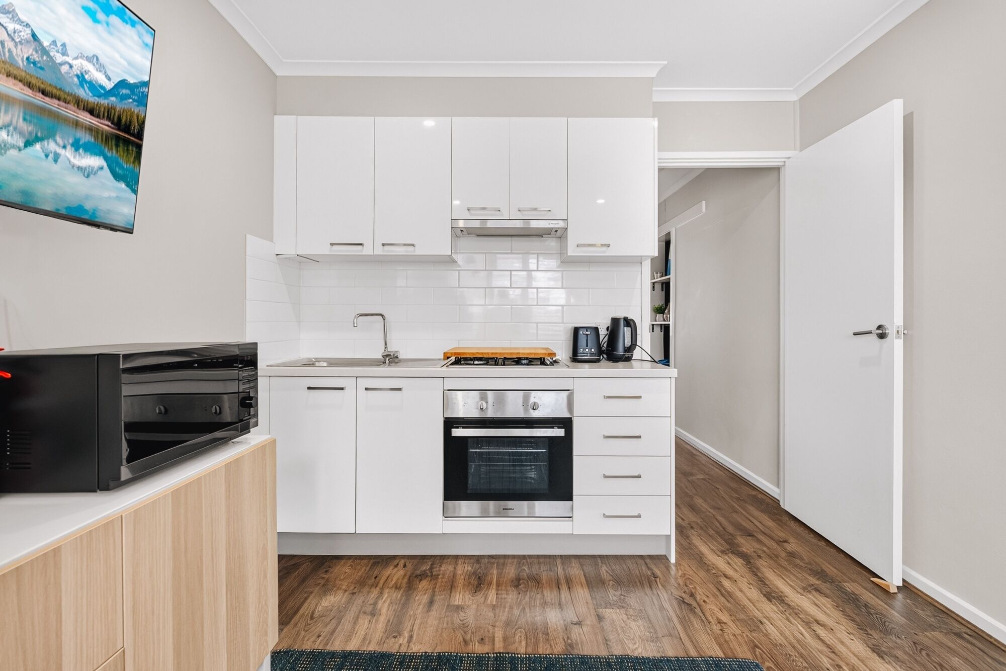 A compact kitchen with white cabinets, a built-in oven, and a coffee maker.