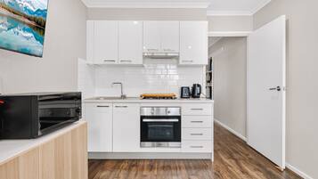 A compact kitchen with white cabinets, a built-in oven, and a coffee maker.