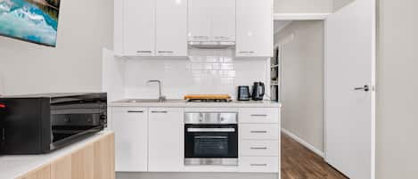 A compact kitchen with white cabinets, a built-in oven, and a coffee maker.