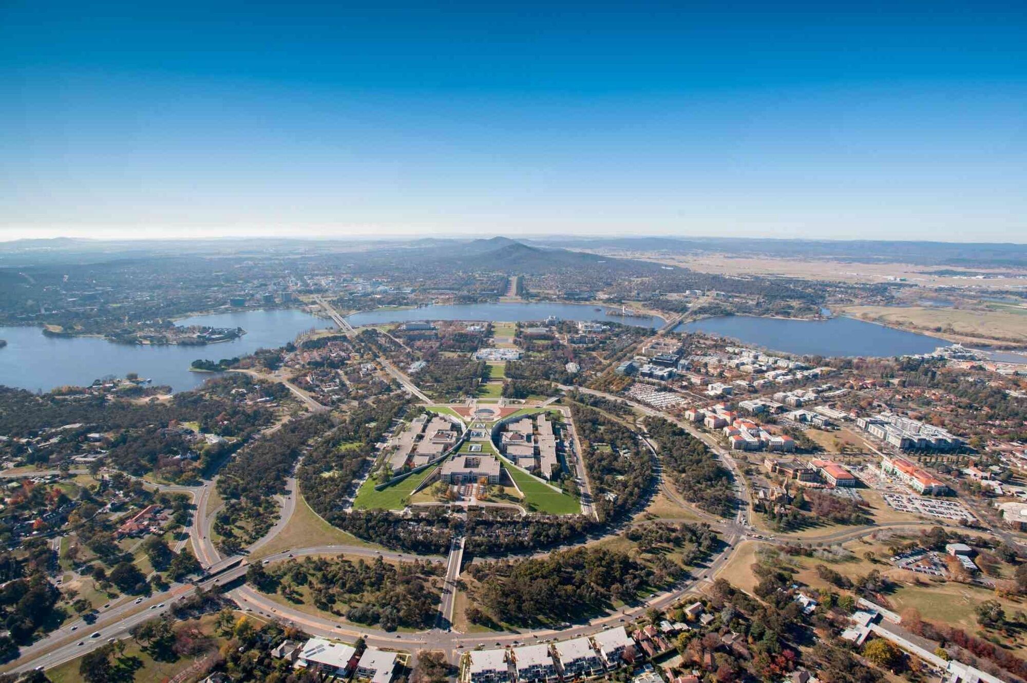 Luchtbeeld van een campus met een groene centrale ruimte, omliggende gebouwen en een meer.