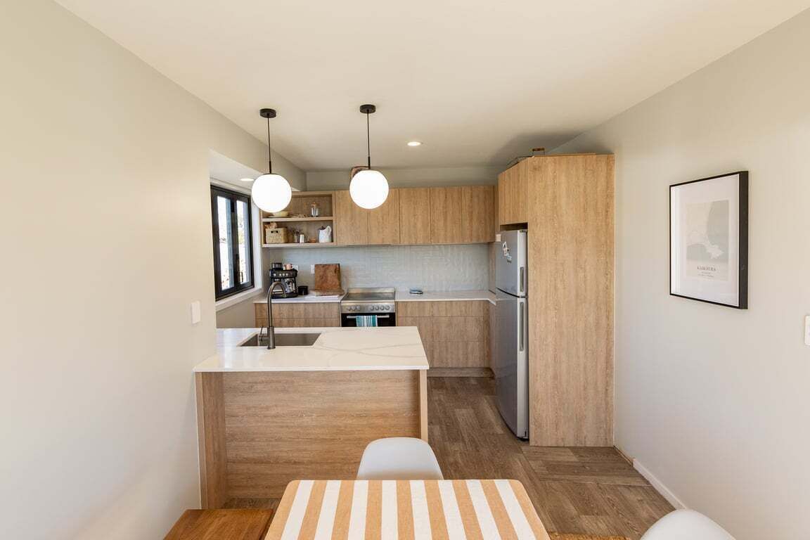 Una cucina compatta con pensili in legno, un'isola centrale e luci a sospensione.
