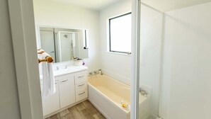 Une salle de bain avec une baignoire, un miroir et une fenêtre.