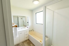 Een badkamer met een bad, een spiegel en een raam.