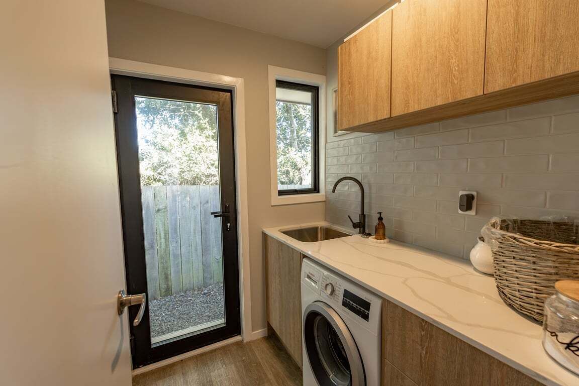 A compact kitchen with a washing machine, a sink, and wooden cabinets.
