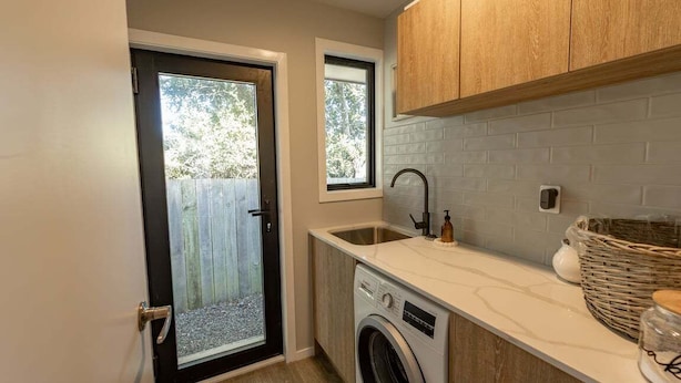 A compact kitchen with a washing machine, a sink, and wooden cabinets.