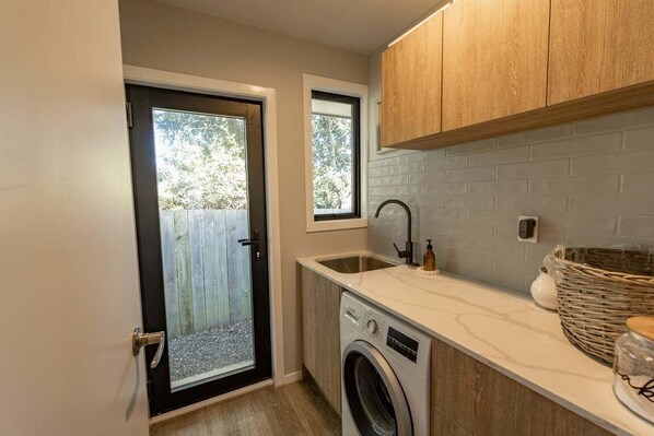 A compact kitchen with a washing machine, a sink, and wooden cabinets.