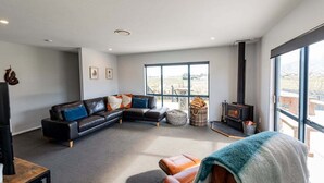 Un salon moderne avec un canapé d’angle, une cheminée et de grandes fenêtres.
