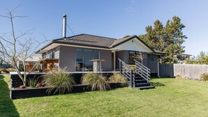 Une maison moderne à deux étages, dotée d’un patio couvert, d’une cheminée et d’une pelouse bien entretenue.