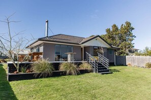 Een modern huis met twee verdiepingen, een overdekte patio, schoorsteen en een verzorgd gazon.