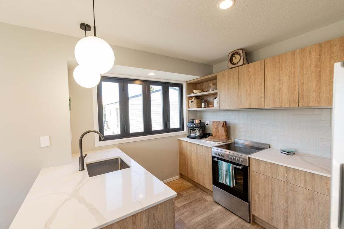 A modern kitchen with a built-in oven, a coffee maker, and a window providing natural light.
