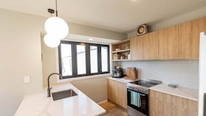 A modern kitchen with a built-in oven, a coffee maker, and a window providing natural light.