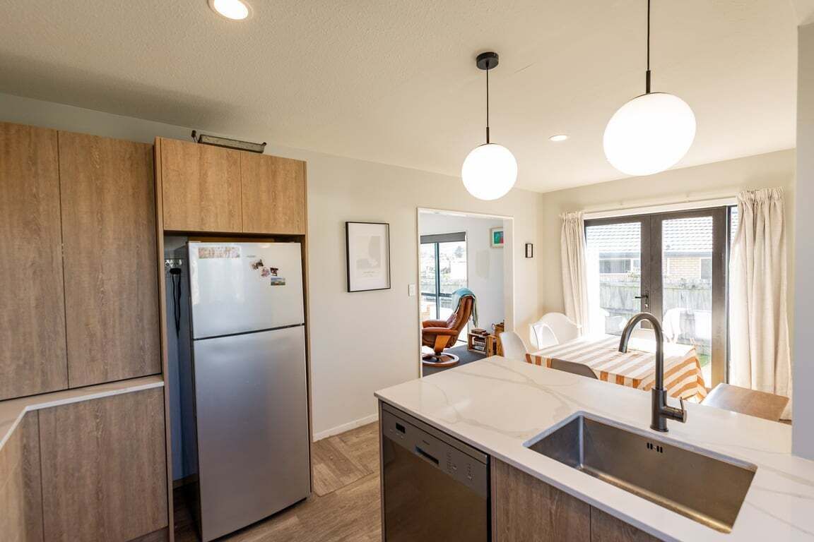 A compact kitchen with a built-in dishwasher, a refrigerator, and a sink with a modern faucet.