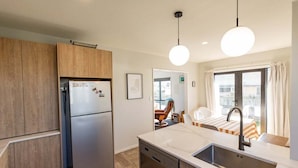 A compact kitchen with a built-in dishwasher, a refrigerator, and a sink with a modern faucet.
