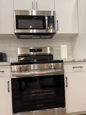 A kitchen with a stainless steel microwave, oven, and stovetop. - Tahee Mountain Lodge 7 (Mara)
