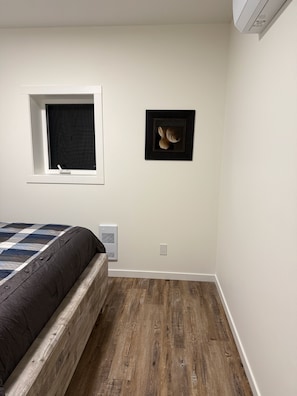 A bedroom with a bed, a window, a wall-mounted air conditioner, and a framed picture. - Tahee Mountain Lodge 7 (Mara)