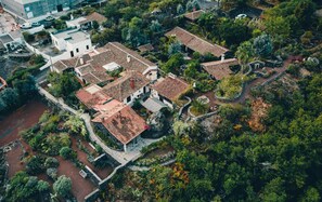 Vista aérea de una zona residencial con casas escalonadas, rodeada de vegetación densa y una pequeña masa de agua.