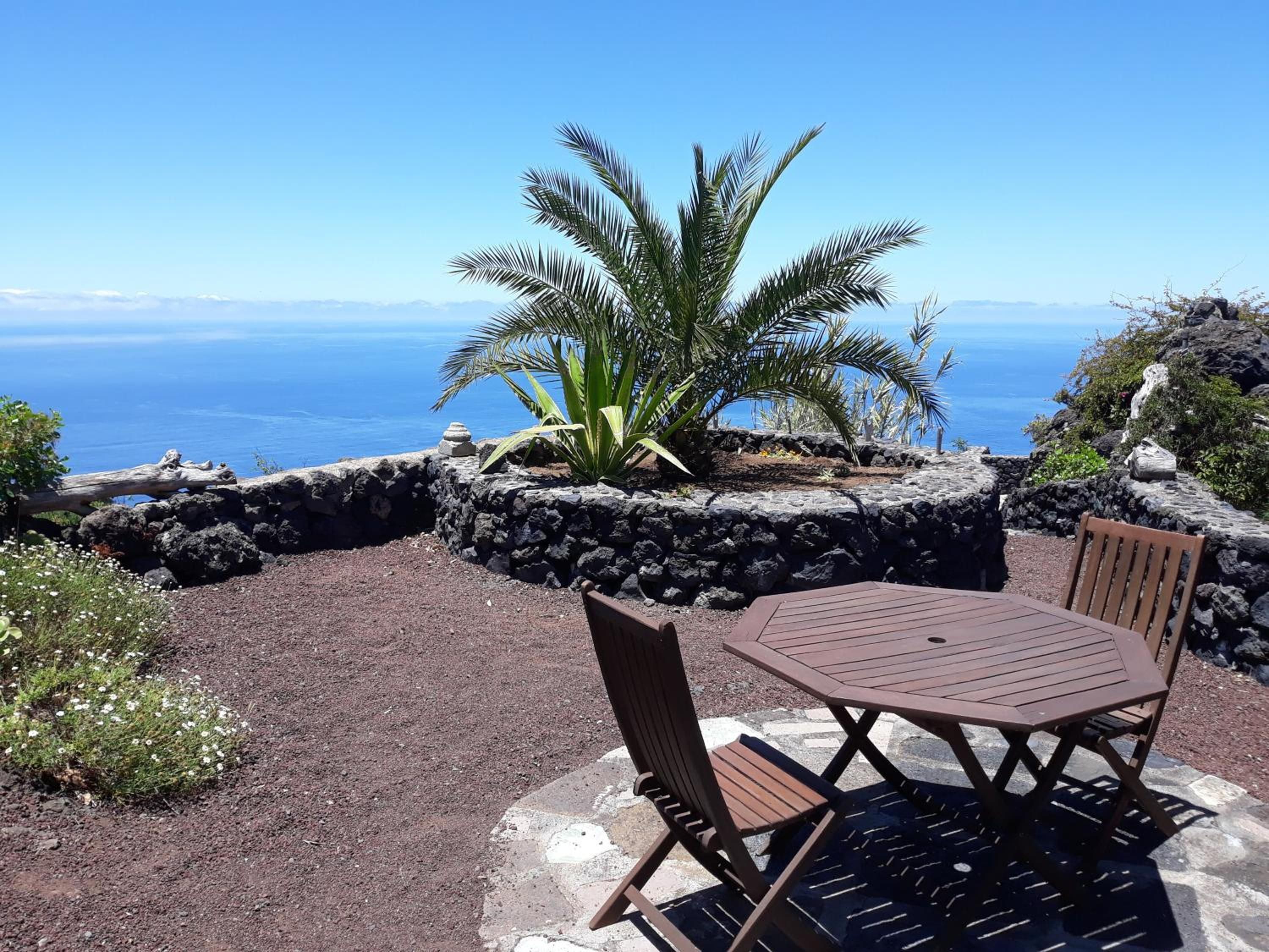 Un área de estar al aire libre con una mesa y sillas, una palmera y vistas al océano.