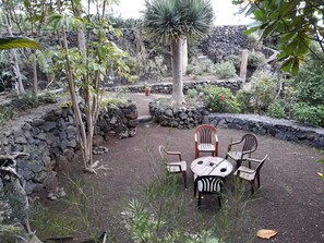 Un espacio al aire libre con muros de piedra y diversas plantas.