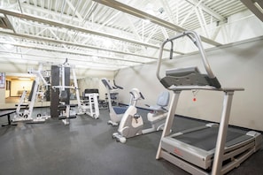 Ein Fitnessstudio mit verschiedenen Trainingsgeräten, darunter Laufbänder, Kraftgeräte und ein Rudergerät.
