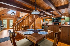 A wooden interior with a dining table, chairs, a staircase, and a kitchen area. - The Equestrian Hideaway (8-minutes from TIEC)! (Rutherfordton)