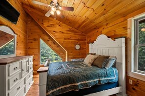 A wooden cabin bedroom with a bed, dresser, and a ceiling fan. - The Equestrian Hideaway (8-minutes from TIEC)! (Rutherfordton)