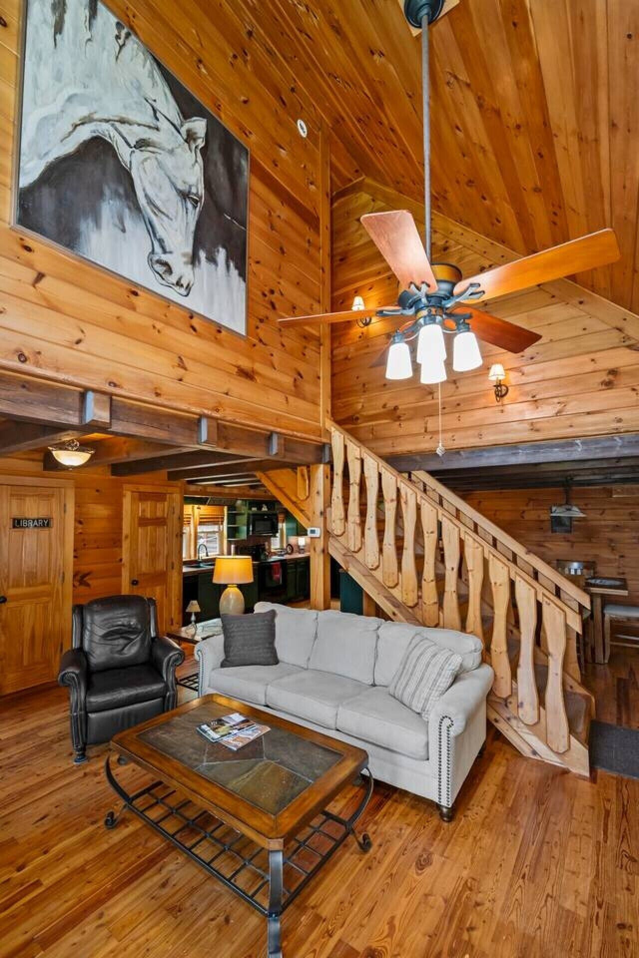Un intérieur en bois avec un escalier, un canapé, une table basse et un tableau accroché au mur.